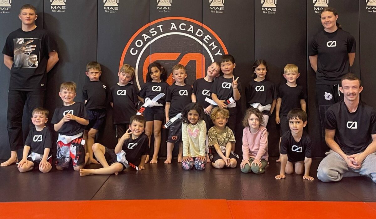 Children in Coast Academy t-shirts sitting on the mats during a Mini Martials kids Jiu Jitsu class in Silverdale.